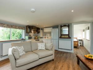 een woonkamer met een bank en een keuken bij Barn Owl Lodge in Stoke Holy Cross