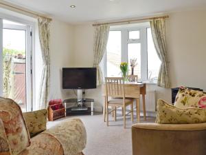 a living room with a couch and a television and a table at Little Orchard in Dursley