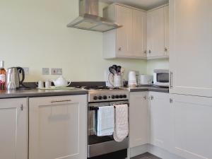 a kitchen with white cabinets and a stove top oven at Little Orchard in Dursley