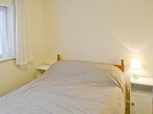 a white bed in a room with a lamp at The Retreat in Cromer
