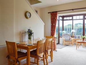 ein Esszimmer mit einem Holztisch und Stühlen in der Unterkunft Bramble Cottage in Meigle