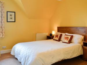 ein Schlafzimmer mit einem großen weißen Bett mit zwei Kissen in der Unterkunft Bramble Cottage in Meigle