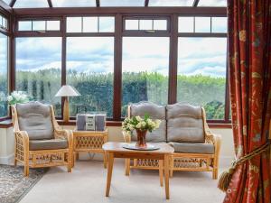 a living room with two chairs and a table at Bramble Cottage in Meigle