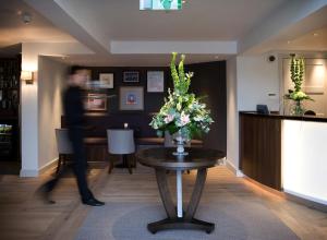 a man walking past a table with a vase of flowers at Castle Hotel & Apartments in Lincoln