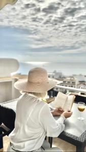 une femme assise à une table en train de lire un livre dans l'établissement Albufeira Holidays Penthouse Sea View, à Albufeira