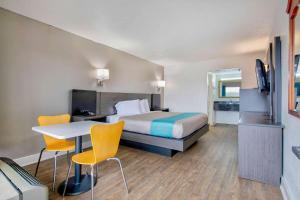 ein Hotelzimmer mit einem Bett, einem Schreibtisch und Stühlen in der Unterkunft Motel 6 Byron, Ga in Byron
