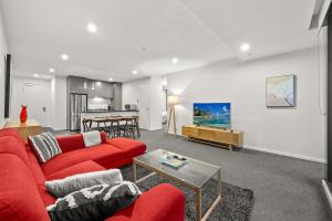een woonkamer met een rode bank en een tafel bij Exclusive Stays - Southbank Grand in Melbourne