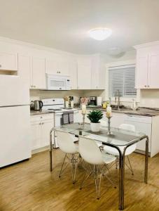 een keuken met een tafel en stoelen en witte kasten bij A Cozy Family get away suite in South Nanaimo in Nanaimo