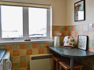 a kitchen with a counter and two windows at Ferry View in Oban