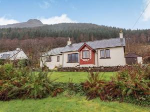 a white and red house with a mountain in the background at Creagan Ruadh in Kintail