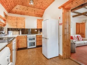 a kitchen with a white refrigerator and wooden cabinets at Creagan Ruadh in Kintail