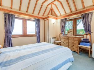 a bedroom with a bed and a dresser and windows at Creagan Ruadh in Kintail