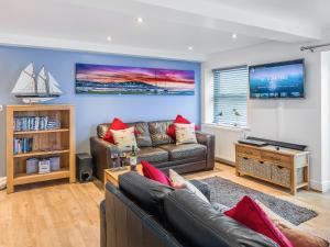 a living room with a leather couch and a tv at Shoreline in Appledore