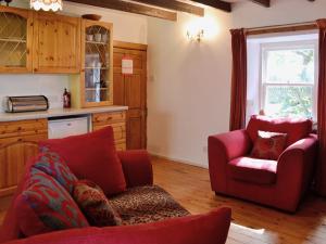 a living room with a red couch and a chair at The Cottage in Saint Cyrus