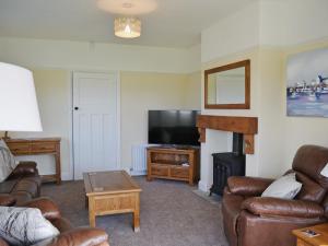 a living room with couches and a tv and a fireplace at Wayside in Beadnell