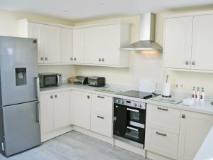 a kitchen with white cabinets and a stainless steel refrigerator at Wayside in Beadnell