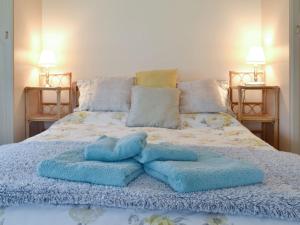 Una cama con dos toallas azules encima. en Ramscliff Cottage en Cheddar