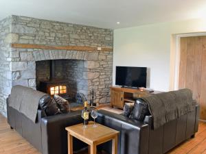 a living room with two leather couches and a stone fireplace at Dolgoed House in Llangadog