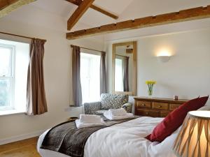 a bedroom with a bed and a chair and windows at Dolgoed House in Llangadog