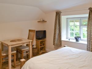 a bedroom with a bed and a table and a television at The Old Post Office in Fordingbridge