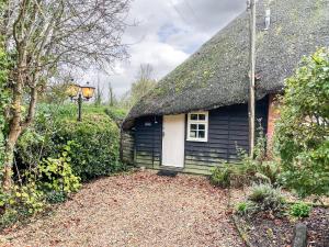 une petite maison noire avec un toit de chaume dans l'établissement The Old Post Office, à Fordingbridge