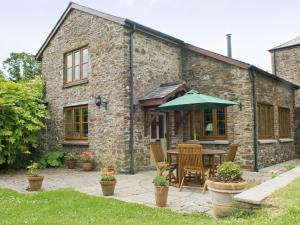 a stone cottage with a table and an umbrella at The Appleloft in Westleigh