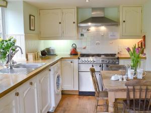 uma cozinha com armários brancos, uma mesa e um lavatório em The Appleloft em Westleigh