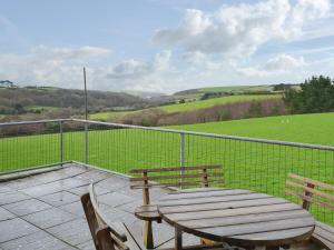 a wooden table and chairs on a patio with a view of a field at Porth View in Saint Mawgan