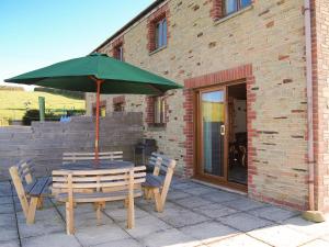 a table and chairs with an umbrella on a patio at Porth View in Saint Mawgan