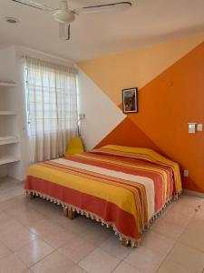 a bedroom with a bed with an orange wall at Viento Casa los 4 elementos in Cancún