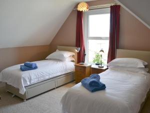 two beds in a bedroom with blue towels on them at Seasands in Sheringham