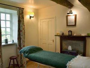 a bedroom with a green bed and a fireplace at Thurst House Farm Holiday Cottage in Ripponden