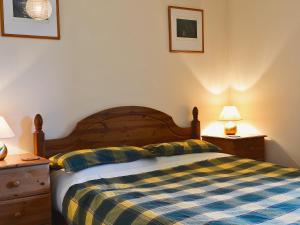 1 dormitorio con 1 cama con manta a cuadros en Cornucopia, en Portree