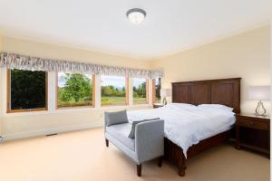 1 dormitorio con 1 cama, 1 silla y ventanas en Season Premiere Winery-Bed & Breakfast in vineyard, en Abbotsford