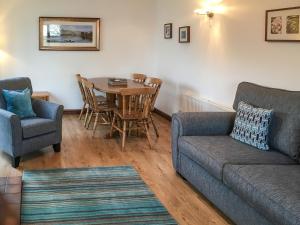 sala de estar con sofá, mesa y sillas en Acorn Cottage en Braithwaite