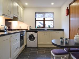 a kitchen with a washing machine and a table at Acorn Cottage in Braithwaite