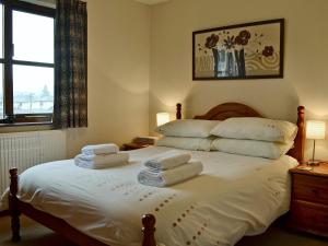 a bedroom with a bed with towels on it at Acorn Cottage in Braithwaite