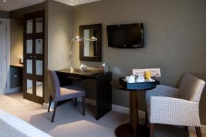 a hotel room with a table, chairs and a television at Castle Hotel & Apartments in Lincoln
