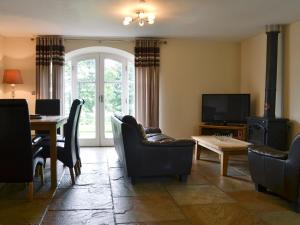 a living room with chairs and a table and a television at Raby Cottage-27764 in Wolsingham