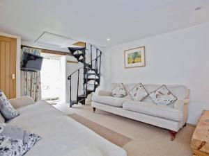 a living room with two white couches and a staircase at The Mill House-tt3 in Warleggan
