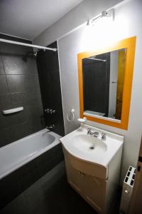 La salle de bains est pourvue d'un lavabo, d'une baignoire et d'un miroir. dans l'établissement South B&B El Calafate, à El Calafate