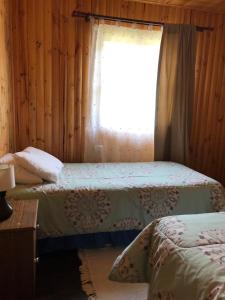 een slaapkamer met 2 bedden en een raam bij Cabaña El Sol Pehuenche Cordillera Talca SanClemente in Talca