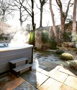 uma banheira sentada num pátio de pedra em The Little Barn @ Bath With LARGE Hot Tub em Bath