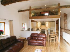 a living room with a couch and a kitchen at The Street Farm Barn in Drayton