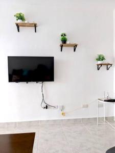 a flat screen tv hanging on a white wall at Moderno apartamento en zona urbana de Santiago. in Santiago de los Caballeros