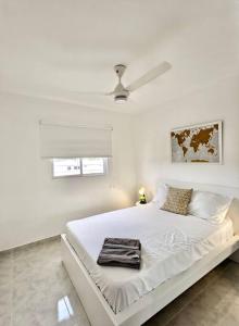 a white bedroom with a large white bed with a ceiling at Moderno apartamento en zona urbana de Santiago. in Santiago de los Caballeros