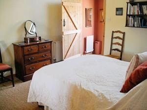 a bedroom with a bed and a dresser and a mirror at Stepping Gate Cottage in Scalby