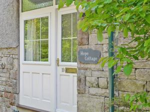 una puerta blanca con una señal en el lateral de un edificio en Hope Cottage, en Lindale