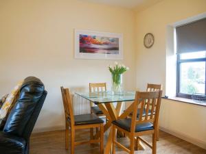 a dining room table with chairs and a vase of flowers at Swallow Cottage in Ferryhill