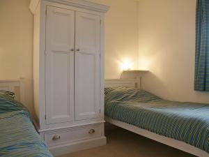 a bedroom with two beds and a large white cabinet at Swallow Cottage in Ferryhill